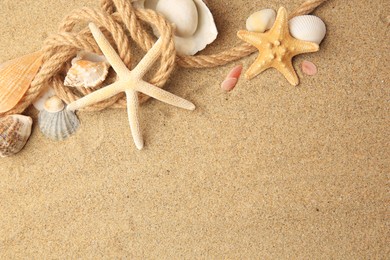 Photo of Beautiful sea stars, shells and rope on sand, flat lay. Space for text