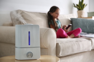 Modern air humidifier and blurred girl on background