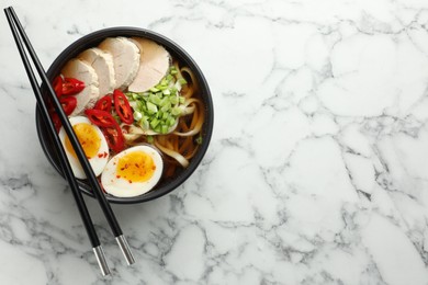 Photo of Delicious ramen in bowl on white marble table, top view with space for text. Noodle soup