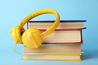 Photo of Books and modern headphones on light blue background