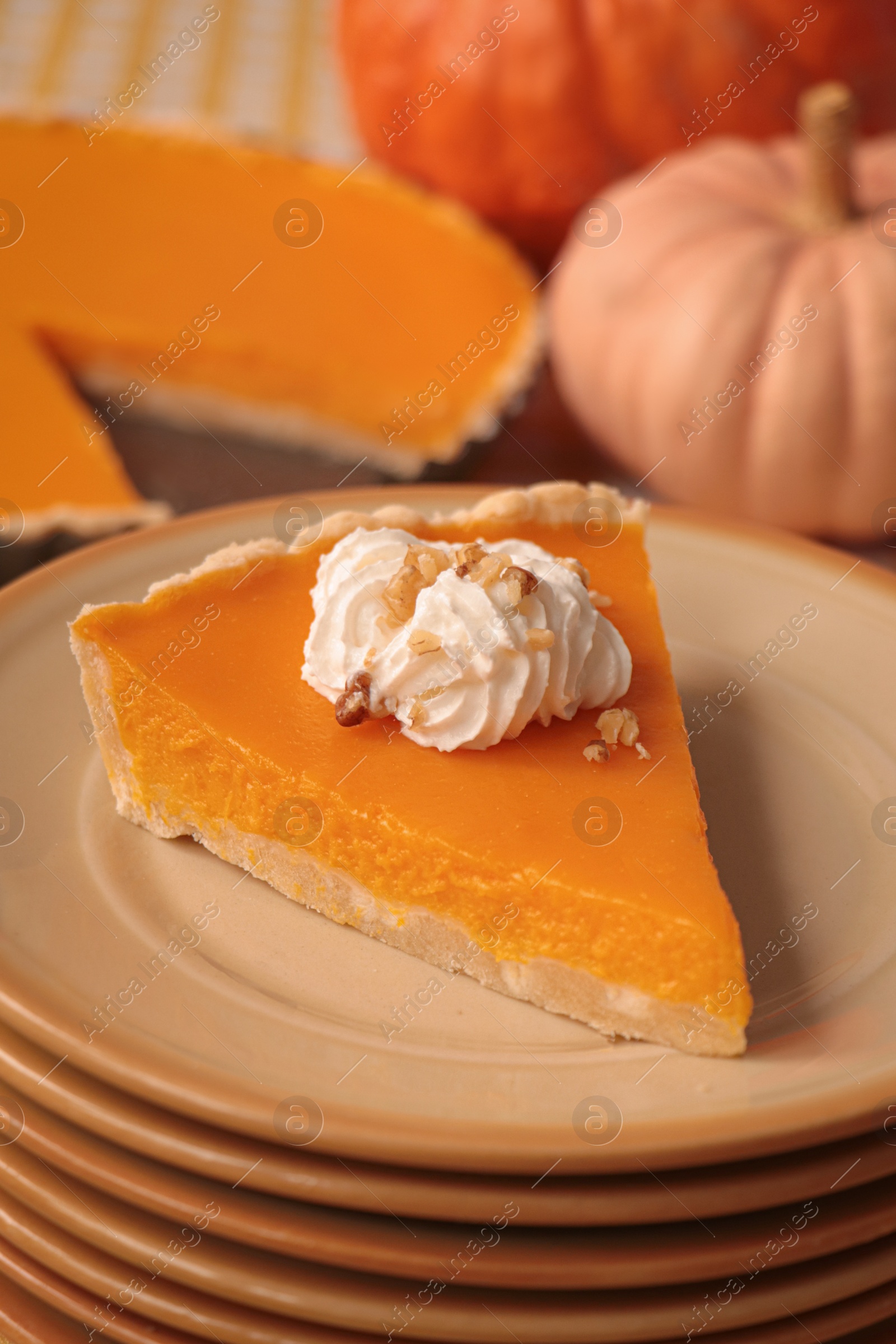 Photo of Stacked plates with piece of fresh homemade pumpkin pie with whipped cream on table