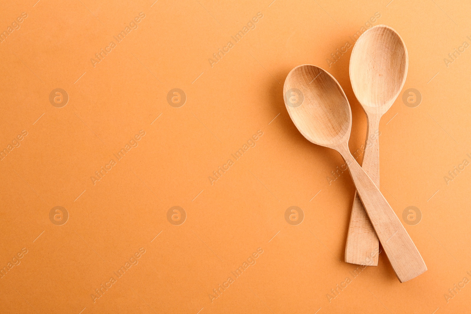 Photo of Clean wooden spoons and space for text on color background, flat lay