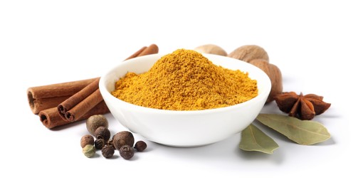 Photo of Dry curry powder in bowl surrounded by other spices isolated on white