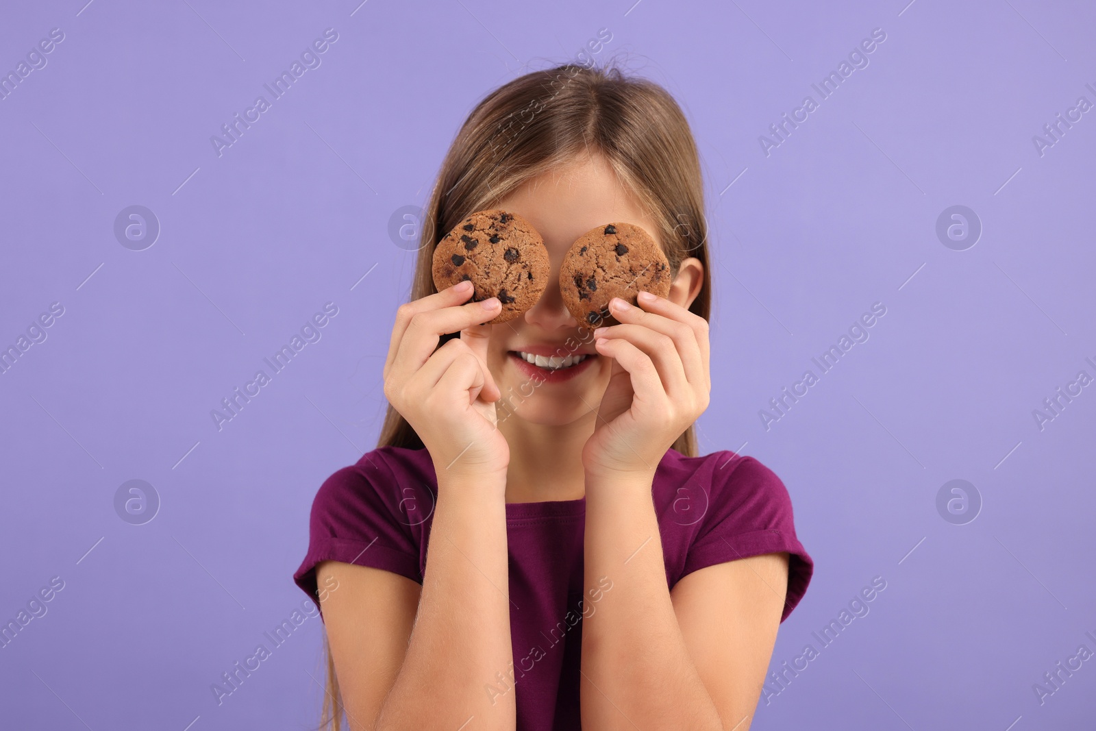 Photo of Girl covering eyes with chocolate chip cookies on purple background