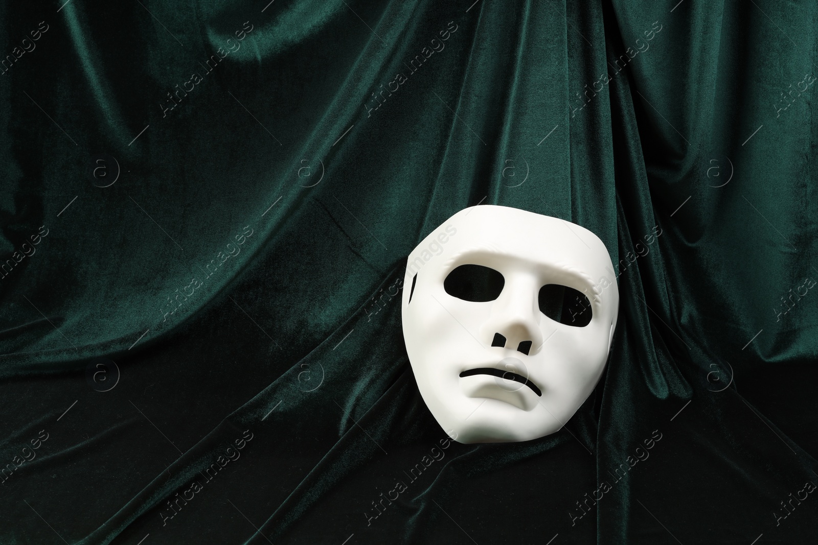 Photo of Theater arts. White mask on green fabric, top view. Space for text