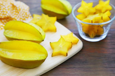 Photo of Delicious cut and whole carambolas on wooden table, closeup