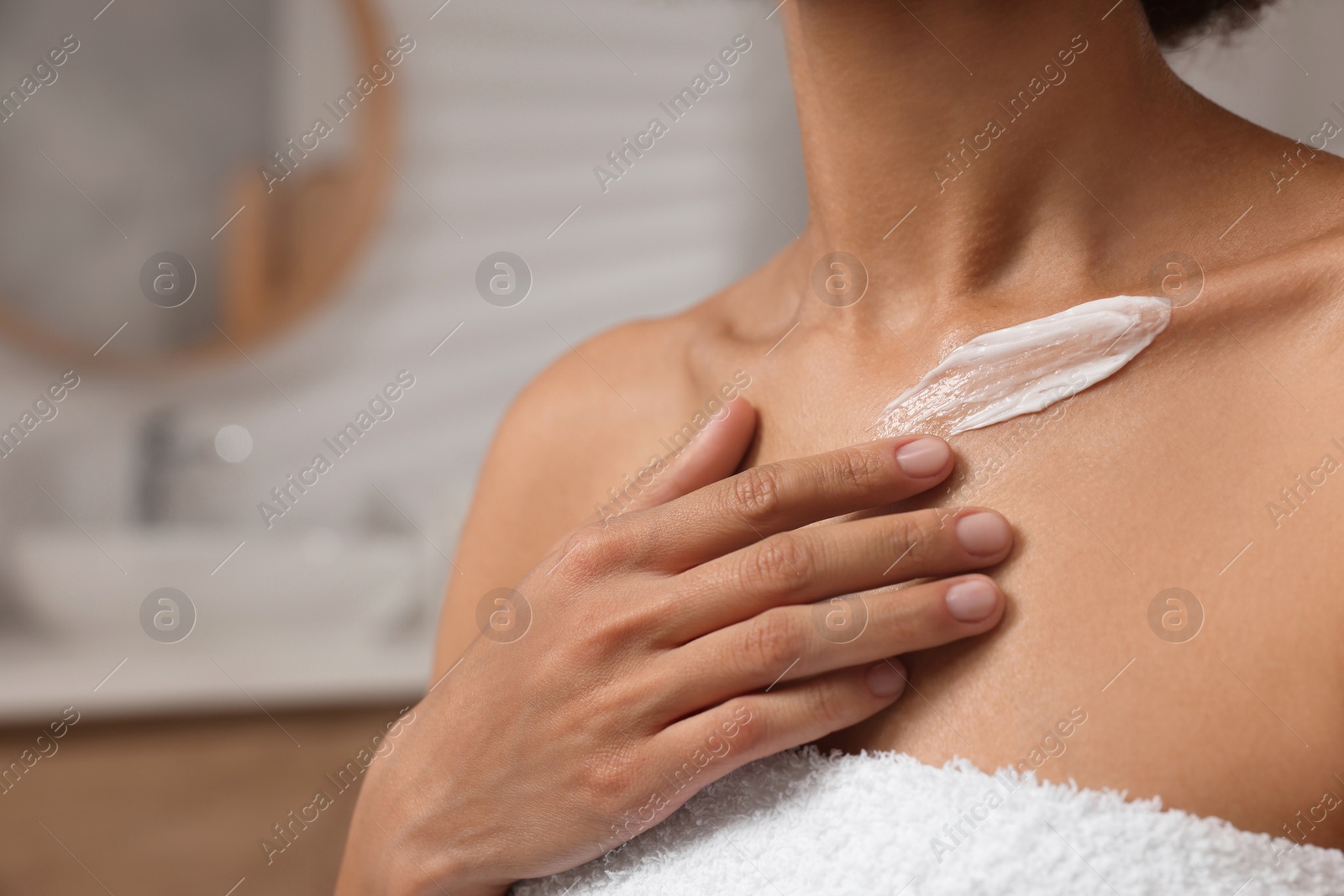 Photo of Woman applying cream onto body in bathroom, closeup. Space for text