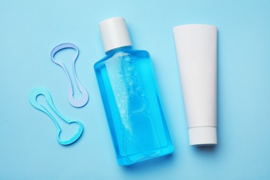 Photo of Tongue cleaners, mouthwash and tooth paste on color background, flat lay