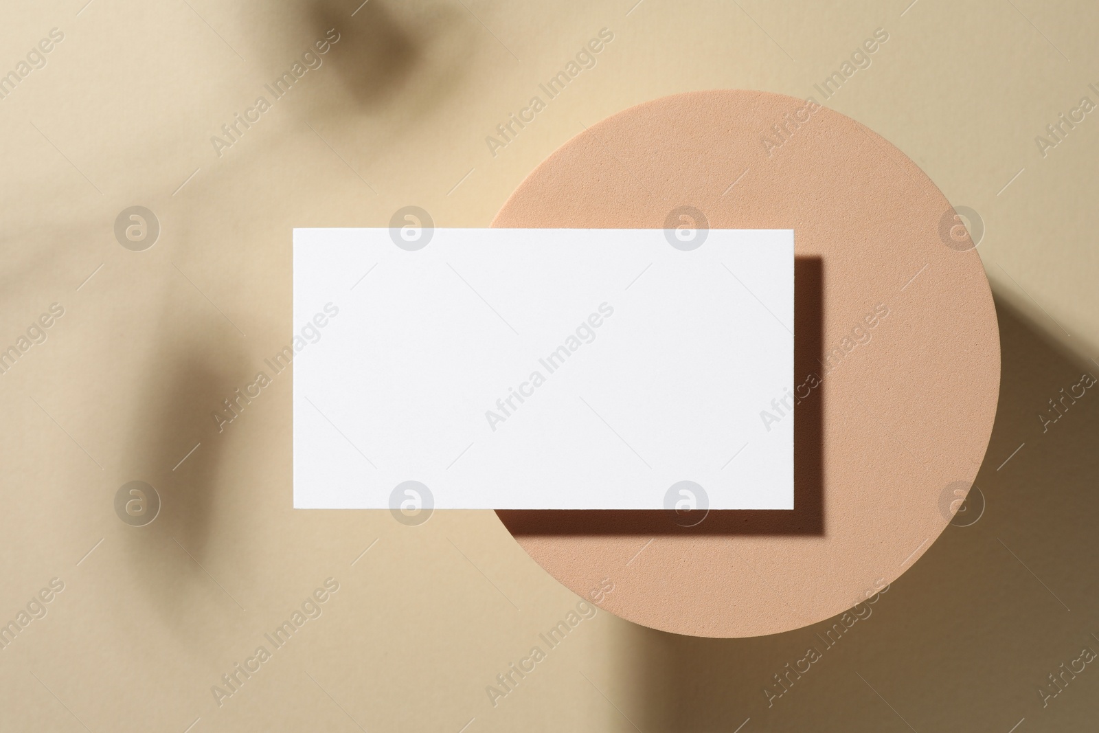 Photo of Empty business card and decorative podium on beige background, top view. Mockup for design