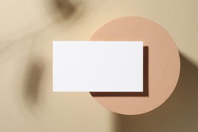 Empty business card and decorative podium on beige background, top view. Mockup for design