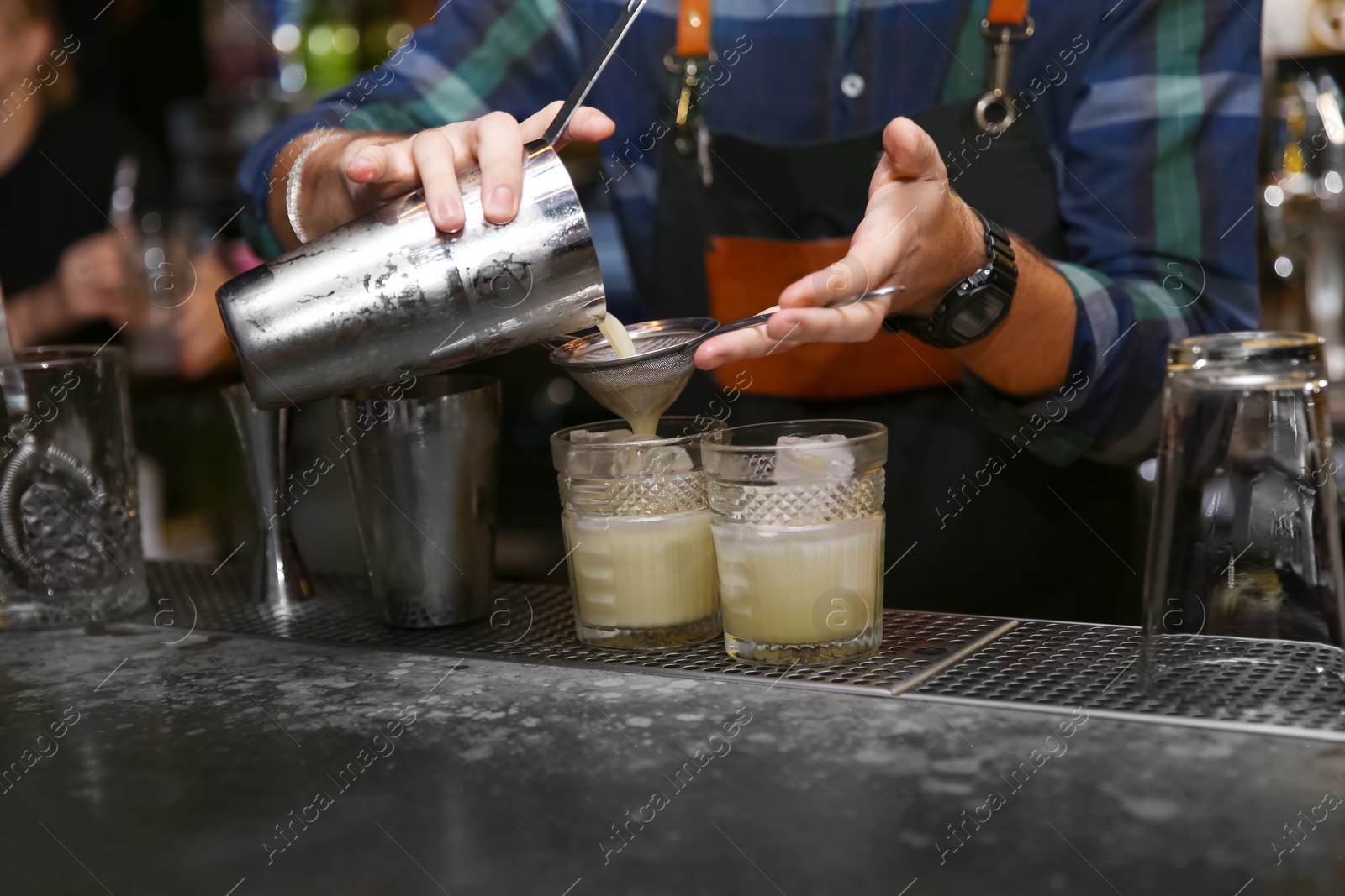 Photo of Bartender pouring tasty cocktail at counter in nightclub, closeup