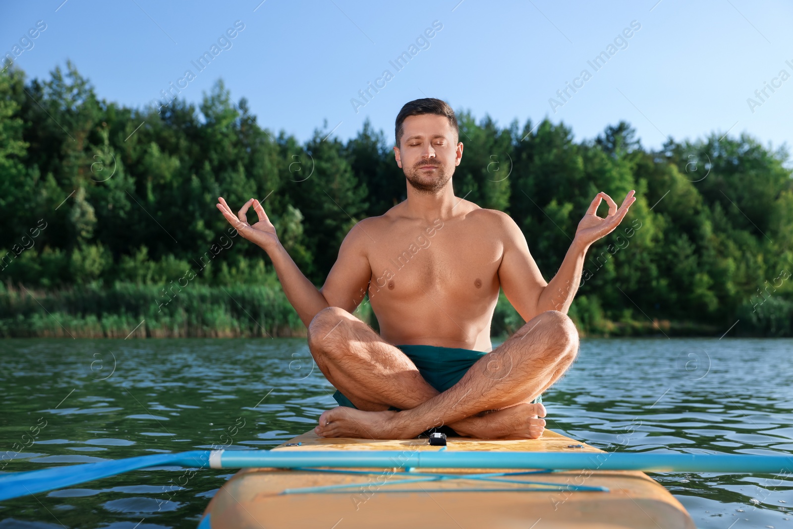 Photo of Man meditating on color SUP board on river