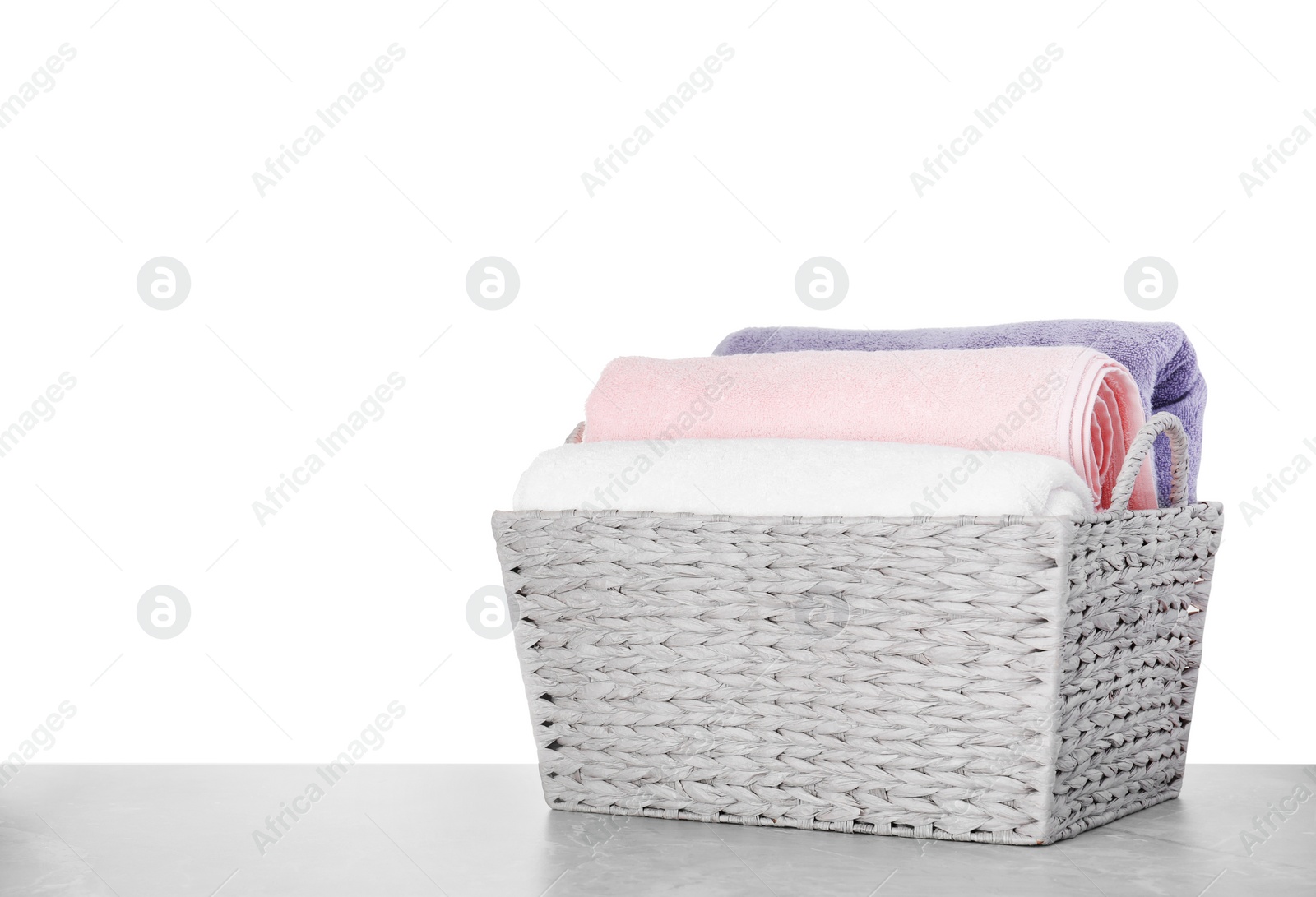 Photo of Basket with clean laundry on grey table, white background