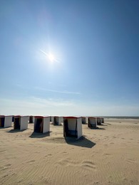 Photo of Many wooden beach huts on seacoast under blue sky