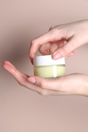 Photo of Woman with jar of cream on beige background, closeup