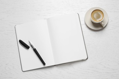 Photo of Open blank notebook, pen and coffee on white wooden table, flat lay