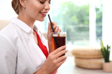 Photo of Young woman with glass of cola at home, closeup. Refreshing drink