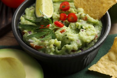 Photo of Delicious guacamole served with nachos chips on table, closeup