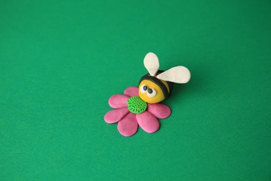 Photo of Bee with flower made from plasticine on green background. Children's handmade ideas