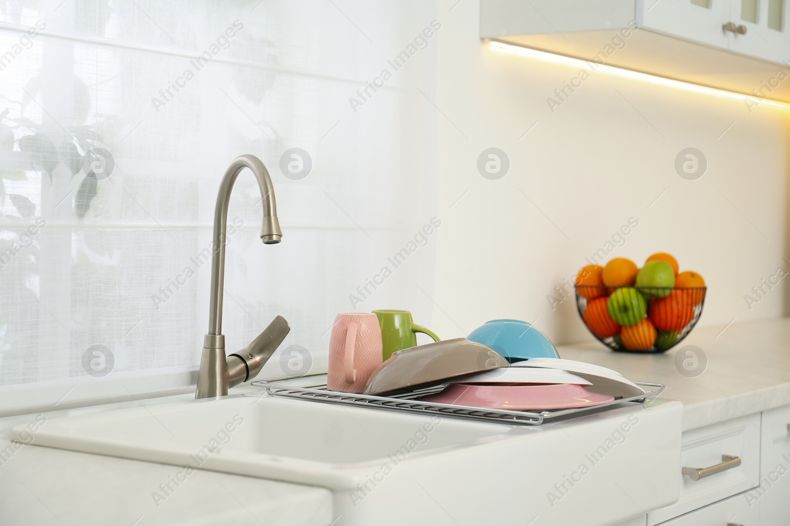 Photo of Drying rack with clean dishes over sink in kitchen