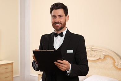 Photo of Man in suit with clipboard indoors. Professional butler courses