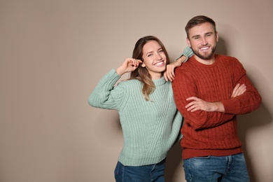 Image of Lovely couple in warm sweaters on beige background. Space for text