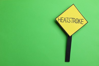 Photo of Sign with words Heat Stroke on green background, top view. Space for text