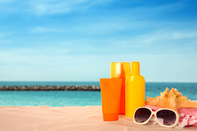 Image of Set of sun protection products and stylish sunglasses on sandy beach. Space for text