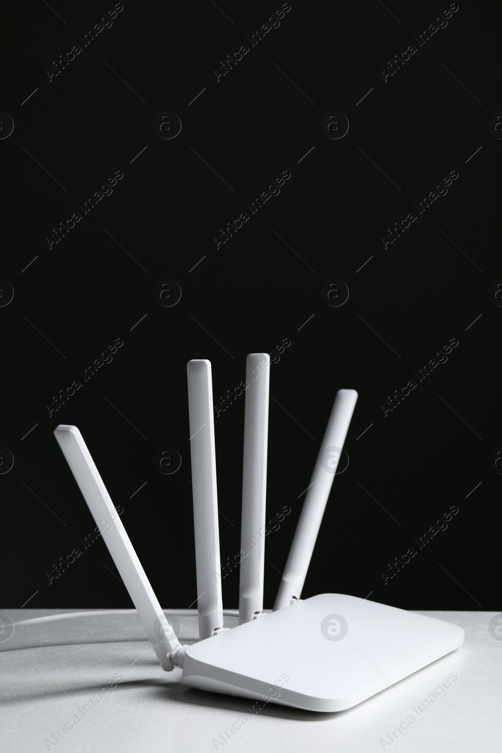 Photo of New modern Wi-Fi router on white table against black background