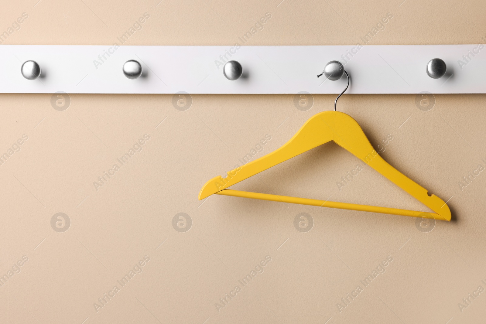 Photo of Rack with empty yellow clothes hanger on beige wall