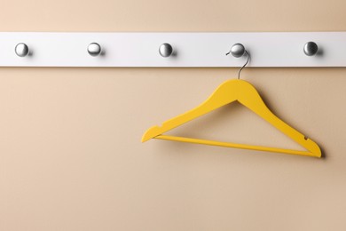Photo of Rack with empty yellow clothes hanger on beige wall