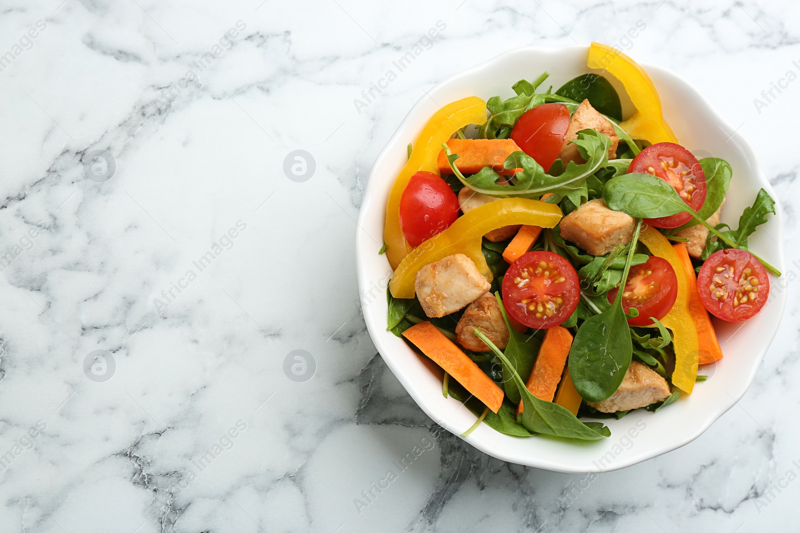 Photo of Delicious fresh chicken salad served on white marble table, top view. Space for text