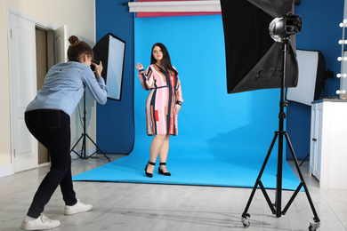 Photo of Photographer taking picture of overweight woman in studio. Plus size model