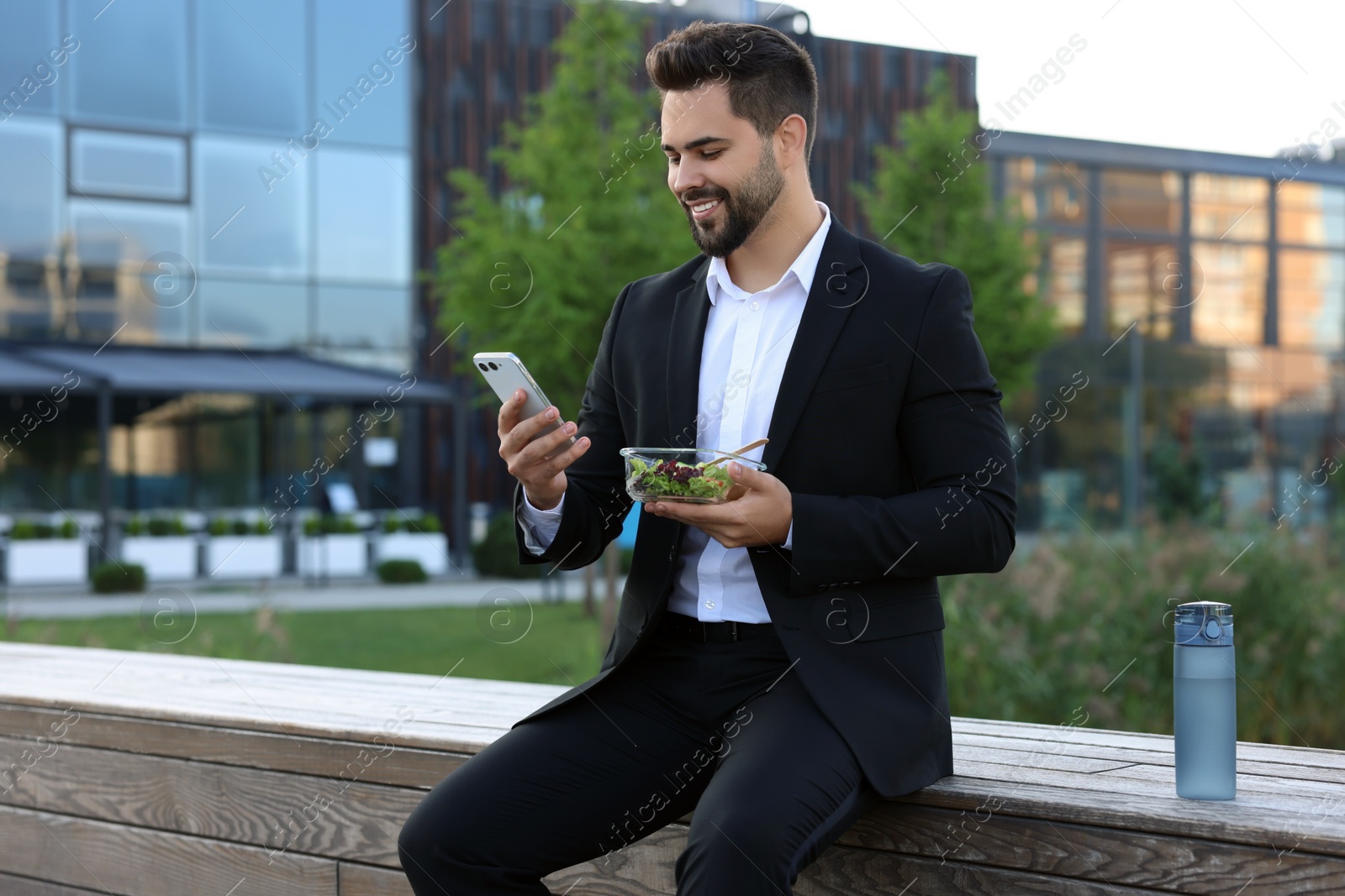 Photo of Smiling businessman with smartphone during lunch outdoors