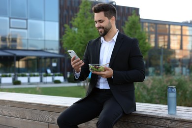 Photo of Smiling businessman with smartphone during lunch outdoors