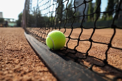 Photo of Tennis ball near net on clay court, closeup