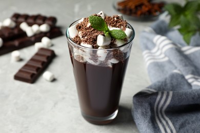 Glass of delicious hot chocolate with marshmallows and fresh mint on light grey table