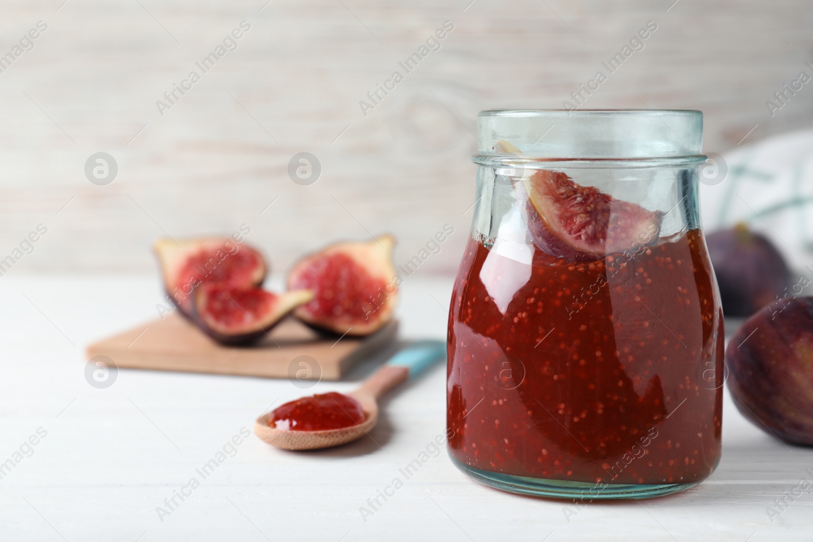 Photo of Delicious fig jam with fresh fruit on white wooden table. Space for text