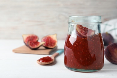 Photo of Delicious fig jam with fresh fruit on white wooden table. Space for text