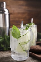 Refreshing cucumber water with basil on wooden table, closeup