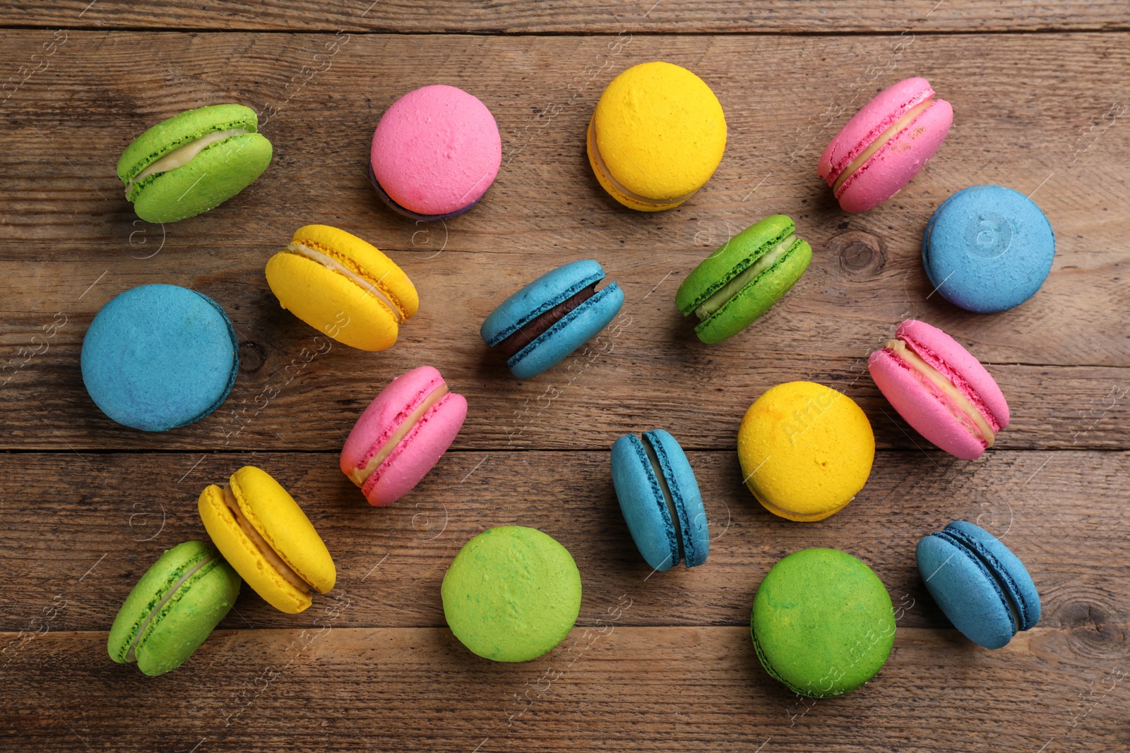 Photo of Flat lay composition with colorful macarons on wooden table