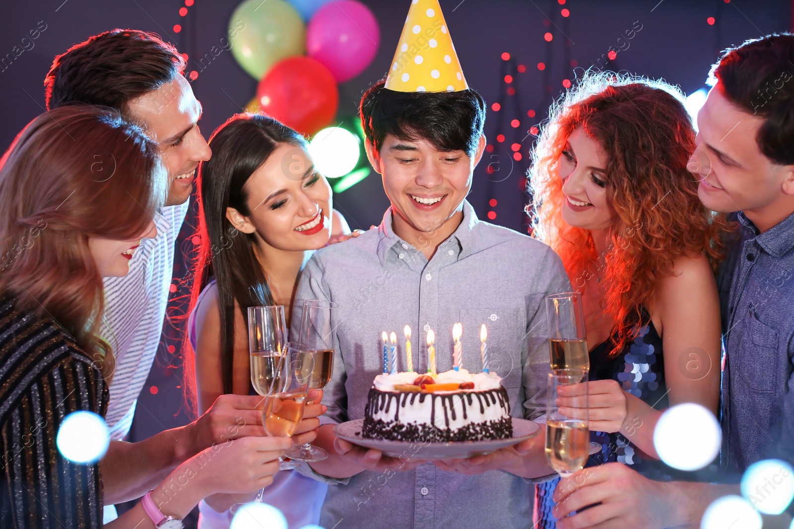 Photo of Young people celebrating birthday with cake in nightclub