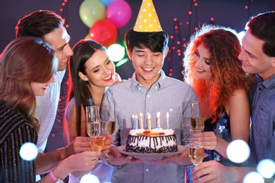 Young people celebrating birthday with cake in nightclub