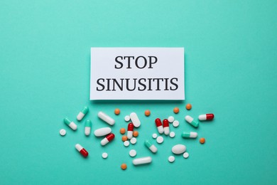 Photo of Card with phrase STOP SINUSITIS and different pills on turquoise background, flat lay