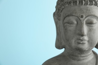 Photo of Beautiful stone Buddha sculpture on light blue background, closeup. Space for text