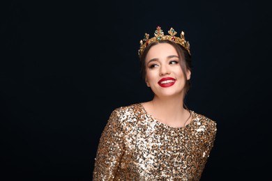 Photo of Beautiful young woman wearing luxurious crown on black background, space for text
