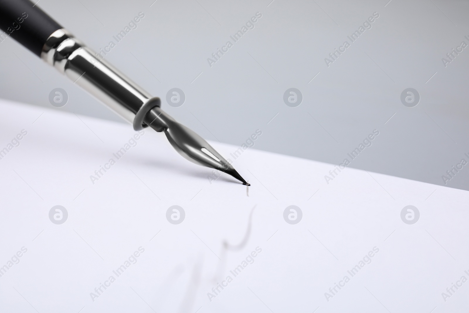 Photo of Signing on sheet of paper with fountain pen against light grey background, closeup. Space for text