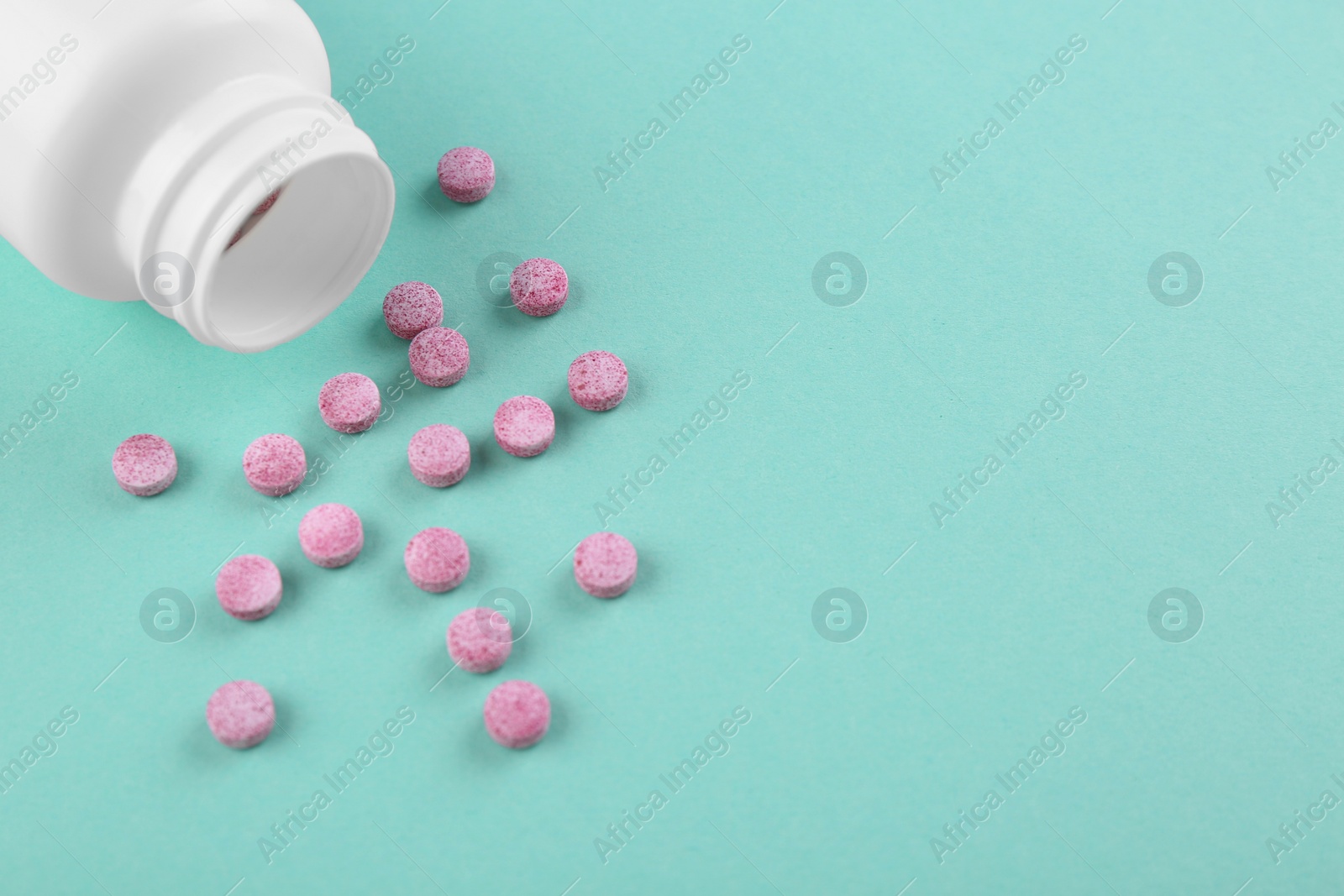 Photo of Bottle and vitamin pills on turquoise background, above view. Space for text