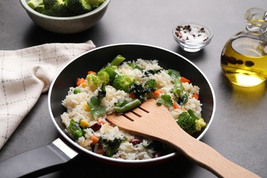 Photo of Tasty fried rice with vegetables served on black table, closeup