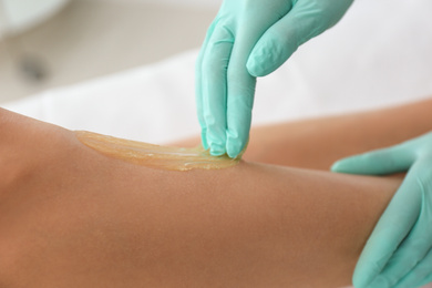 Woman getting wax epilation of legs in salon, closeup